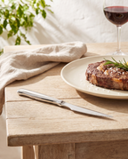 Cuchillo chuletero Zurique sobre una mesa de verano con carne a la brasa