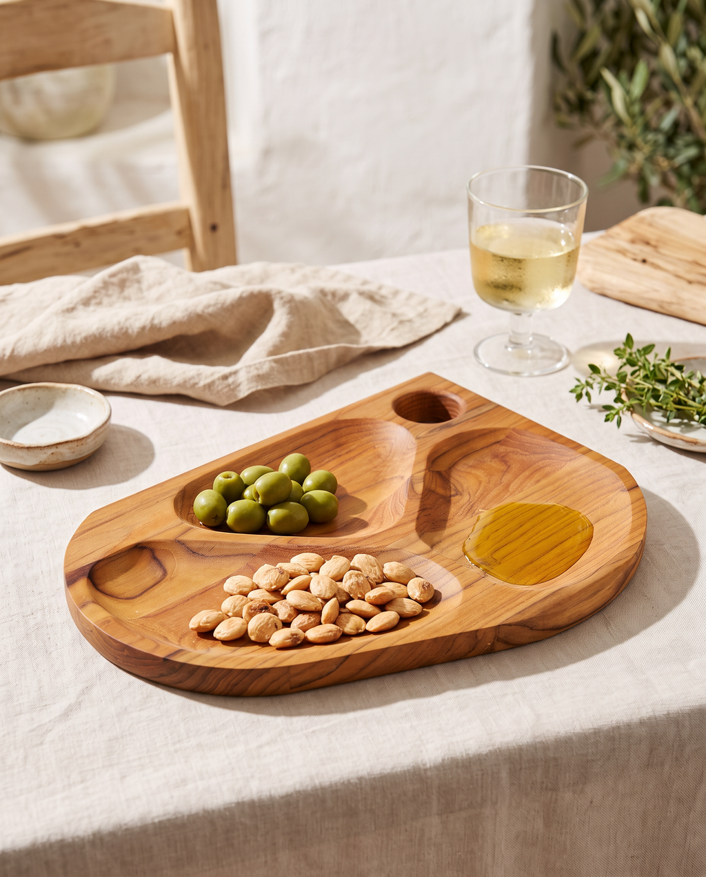 Tabla de aperitivos Folium con aceitunas y almendras en una mesa de verano