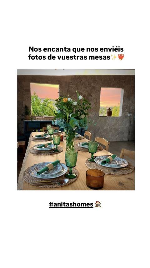 Mesa larga puesta con vasos verdes y centro de flores